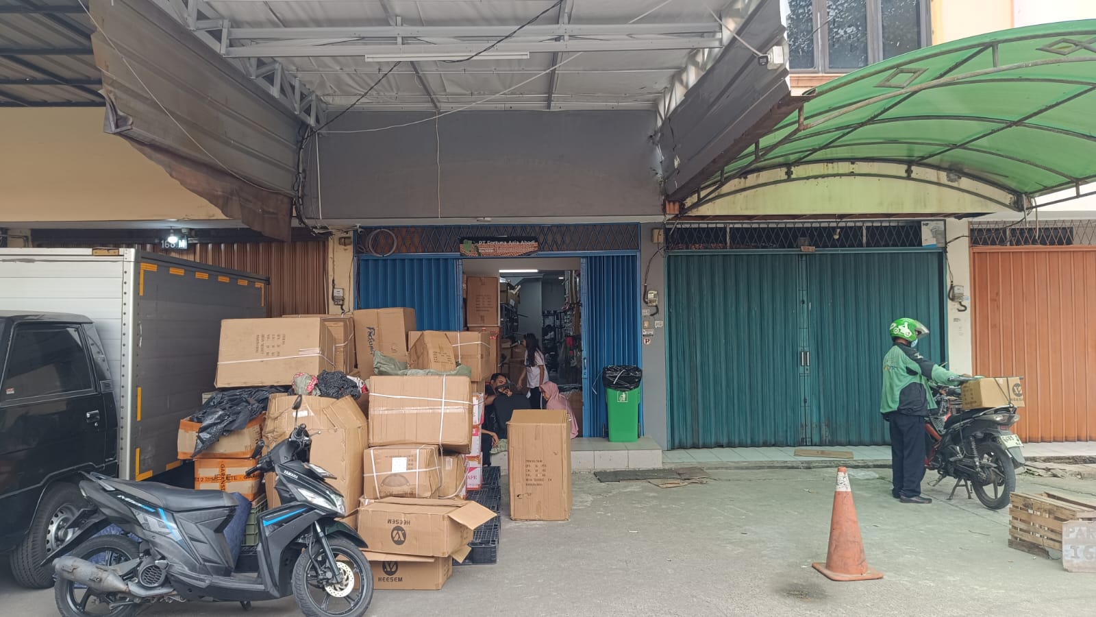 Aktivitas operasional di area penyimpanan dengan kendaraan dan sejumlah kotak.